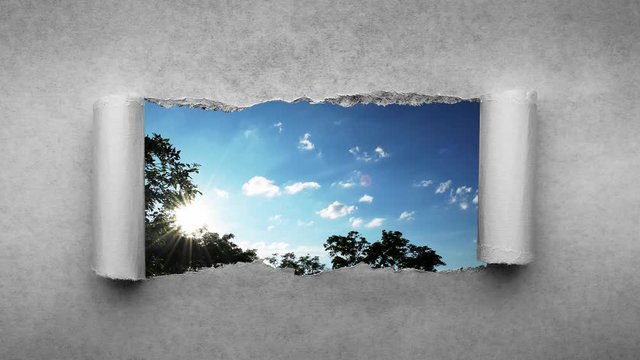 Creative 4k time laps video of fast moving clouds in the blue sky at sunset witn sunflare that are visible through a hole with torn edges in old retro grunge vintage paper.