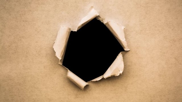 Creative 4k time laps video of a glowing full moon in the night sky with floating clouds, which is visible through a circle hole with torn edges in old retro grunge vintage paper.