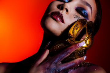 Fashion portrait of a young woman with closed eyes and creative make-up, body art with a masquerade...