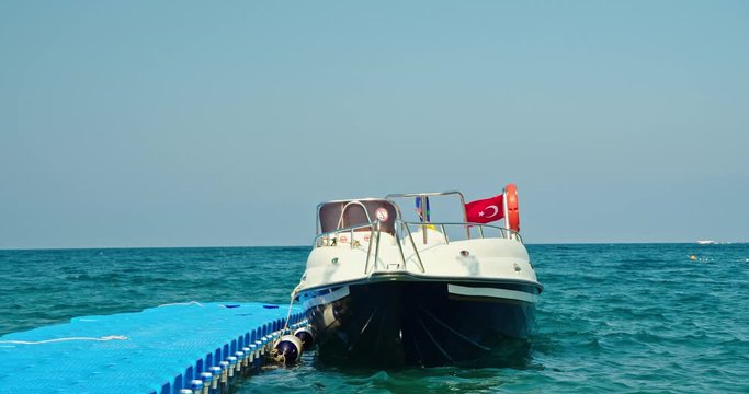 One motor boat in the Mediterranean is moored to the pier. On board the flag of Turkey. Boat for parasailing and other outdoor activities at sea.