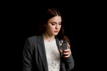 Portrait of a woman drinking water. Smiling girl. Portrait on a black background