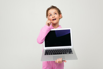 Closeup portrait of an attractive young girl in a pink suit showing a laptop screen with a mockup on a white background