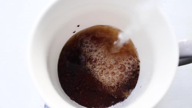 Making Instant Coffee. Top Overhead View Of Water Pouring Into Glass Cup With Instant Coffee Granules