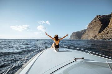 Woman enjoying ocean voyage sitting back on the yacht nose while sailing near the breathtaking...