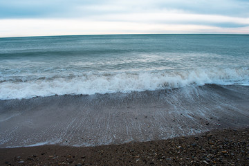 Cold blue sea at sunset. Waves and clouds. Coastline. The waves. The village of Arkhipo-Osipovka.