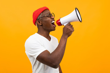 black african man speaks in megaphone on isolated yellow background
