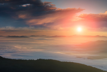 Fototapeta na wymiar Panoramic landscape of colorful sunrise in the mountains. View on foggy hills covered by forest. Concept of the awakening wildlife.