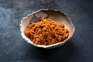 Traditional brown muscovado sugar offered as closeup in a rustic earthenware dish with copy space
