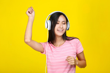Obraz na płótnie Canvas Beautiful woman with headphones on yellow background