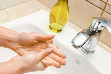 A Washing hands with soap under the faucet with water
