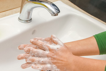 A Washing hands with soap under the faucet with water