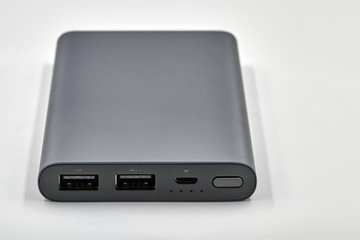 External dark powerbank with two usb outputs on a white background. Powerbank for charging mobile devices. Closeup