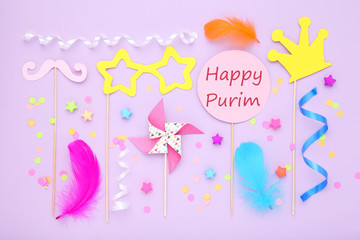 Purim holiday composition. Party supplies with text Happy Purim on purple background