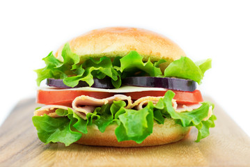 Fresh sandwich with vegetables and ham on the wooden board isolated on white background