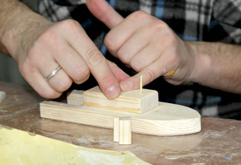 The man glues the part to the workpiece. Master class on manufacturing of wooden ship