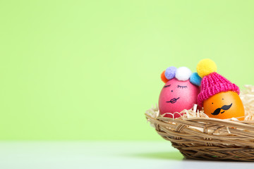 Cute easter eggs in basket on green background