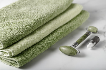 Jade facial roller and serum for anti-aging skin massage on a marble table