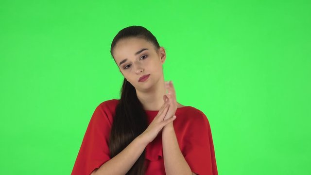 Portrait of pretty young woman is clapping her hands with dissatisfaction. Green screen