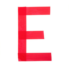 Letter "E" made from red construction adhesive tape. Isolated on white background