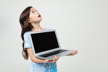 surprised teenager girl holding a laptop with a mockup for inserting a website on a white studio background