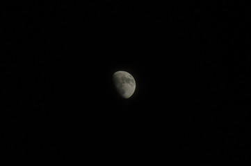 Gey moon over dark black sky at night