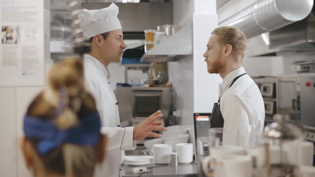 Chef talking to waiter in a commercial kitchen.