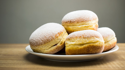 Donuts lie on a wooden table. Fresh hot donuts on a saucer.