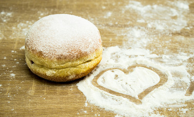 Donut sprinkled with icing sugar. Heart made of flour.