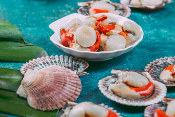 Obraz na płótnie Canvas Raw fresh seafood shellfish scallops on blue background