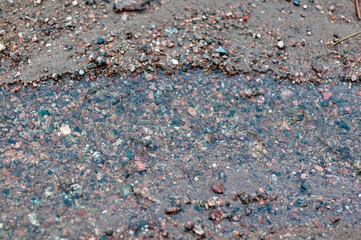 A creek in the sand on the shore of a large lake in early spring, melting ice near the shore on a cloudy spring day.