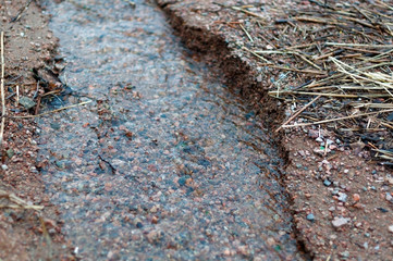 A creek in the sand on the shore of a large lake in early spring, melting ice near the shore on a cloudy spring day.