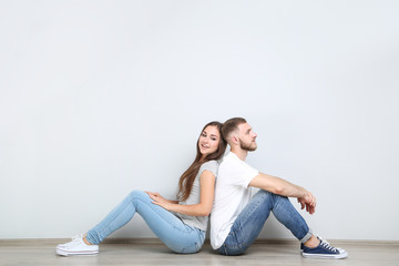 Happy young couple sitting by the back to each other