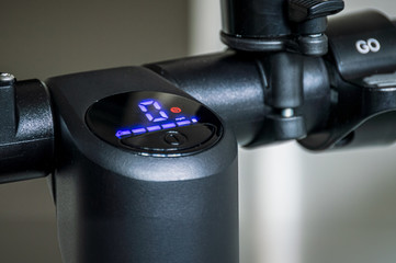 Close up display screen and power button on electric scooter handlebar.