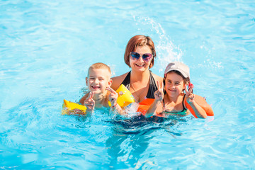beautiful young mother with little son and daughter in pool.