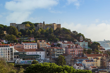 View of the Sao Jorge Castle (Saint George Castle, Castelo de Sao Jorge) and old buildings at the historical Alfama district in downtown Lisbon, Portugal, on a sunny day in the summer. 