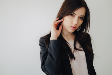 Young attractive emotional girl in business-style clothes on a plain white background in an office or audience