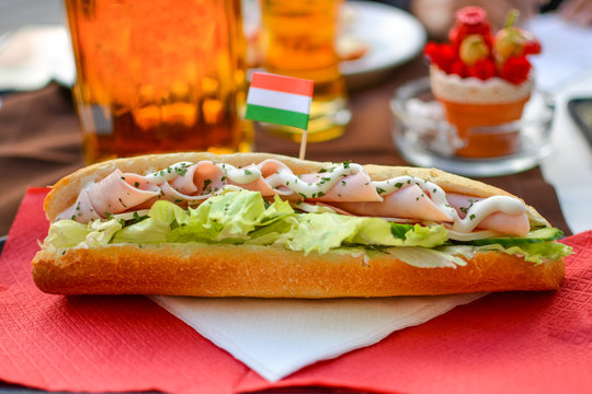 A colorful and well presented lunch of a club sandwich and beers at a sidewalk cafe, complete with a Hungarian flag in Budapest,  Hungary.