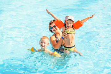 beautiful young mother with little son and daughter in pool.