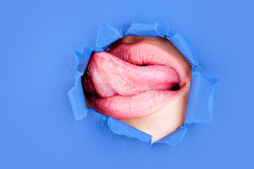 Beauty concept. Lips. Lipstick and pomade. Tongue. Pink color peep into the slit of colored paper....