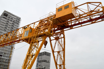Fototapeta na wymiar High heavy yellow metal iron load-bearing construction stationary industrial powerful gantry crane of bridge type on supports for lifting cargo on a modern construction site of buildings and houses