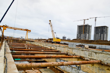 A construction site with specialized professional equipment and cranes during the construction of a modern line of the underground metro station in the big city of the metropolis