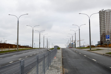 Large wide asphalt road highway avenue city street with lanterns on the sidelines