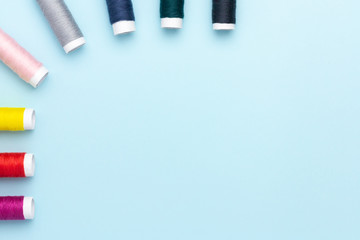 Colorful sewing threads on a blue background.