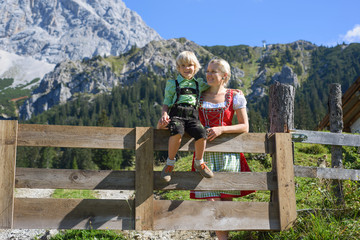 Fototapeta na wymiar Young Bavarian family in a beautiful mountain landscape. Happy mother and little son in traditional Bavarian clothes