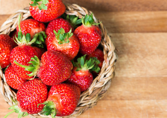 Fresh ripe strawberries in basket on a wooden background