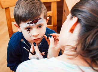little cute child making facepaint on birthday party, zombie Apocalypse facepainting, halloween preparing concept, lifestyle people