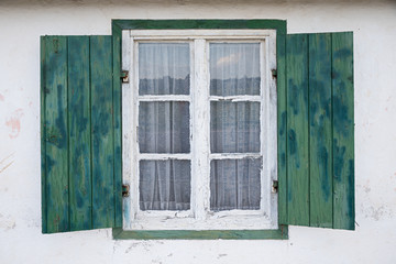 Fototapeta na wymiar opened wooden window with green shutters, white facade