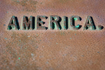 Weathered America message in raised lettering with splotches of green patina with metal copy space 