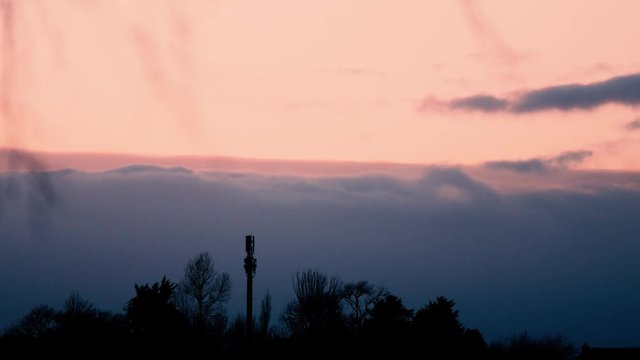 Time lapse of winter sunset on East coast of Ireland. Features trees, railway signal and rolling clouds with subtle change of colours in the sky.