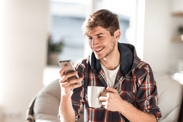 attractive young man drinking coffee and reading SMS.